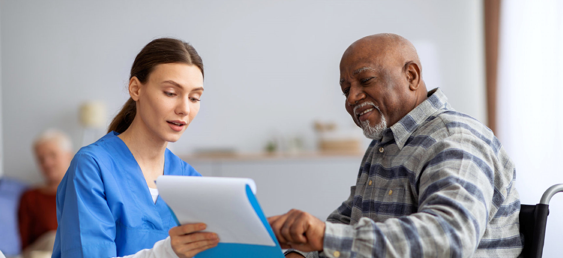 caregiver and an elderly man checking a file